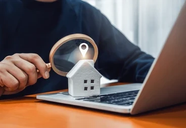 Magnifying glass over a model house on a laptop